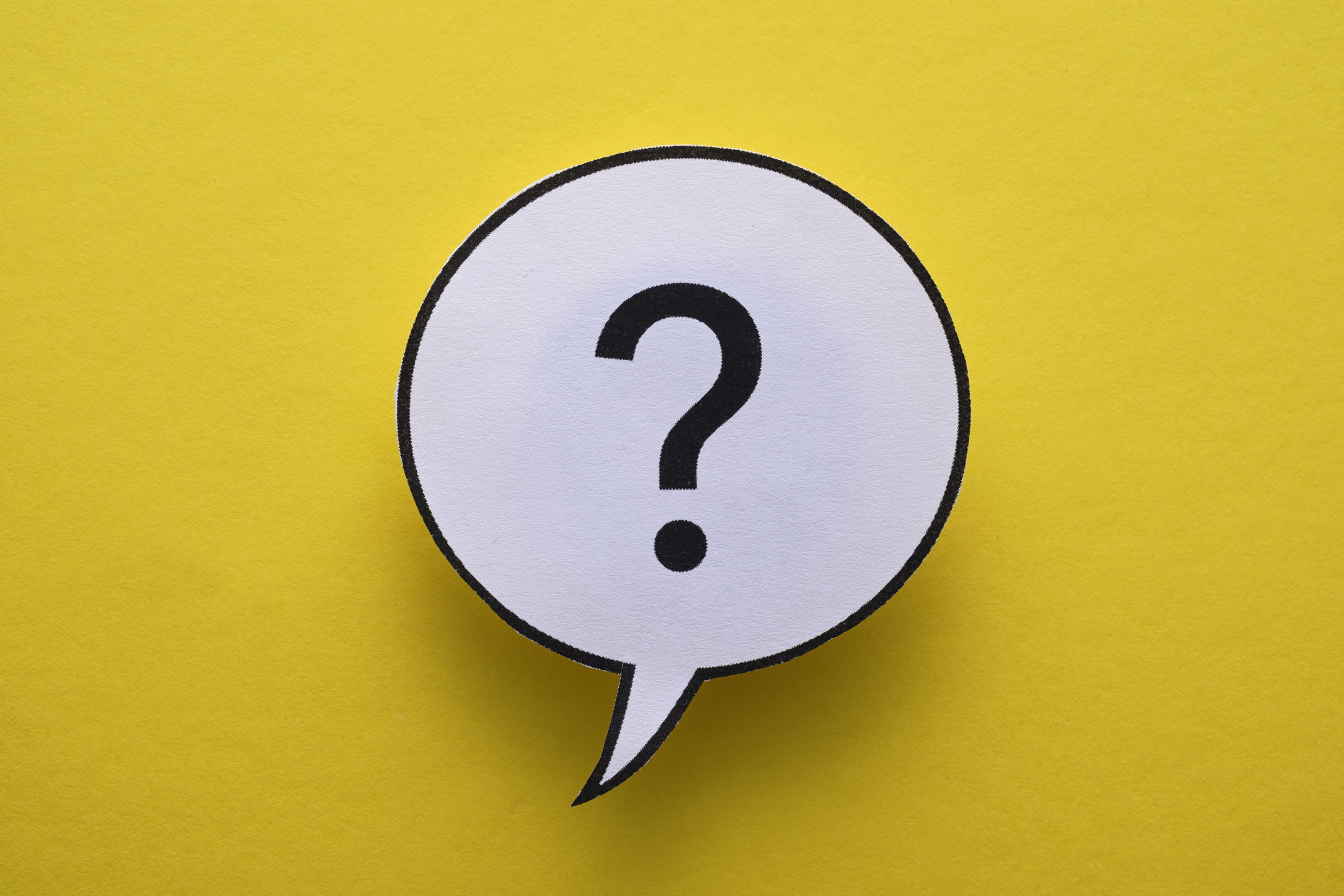 Circular speech or thought bubble with question mark floating over a yellow background with shadow and copyspace