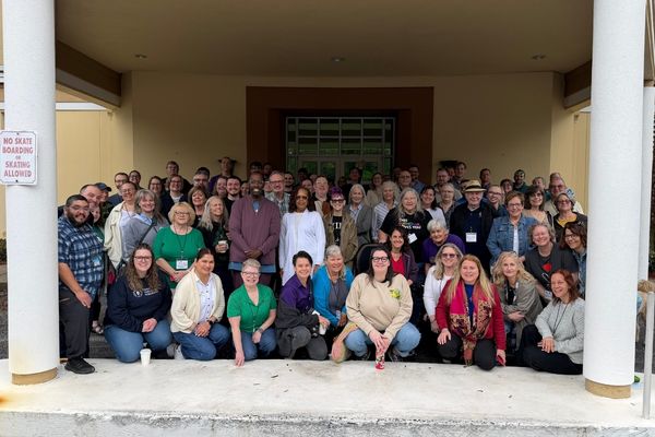 A large group of people posing for a photograph in front of a building entrance.