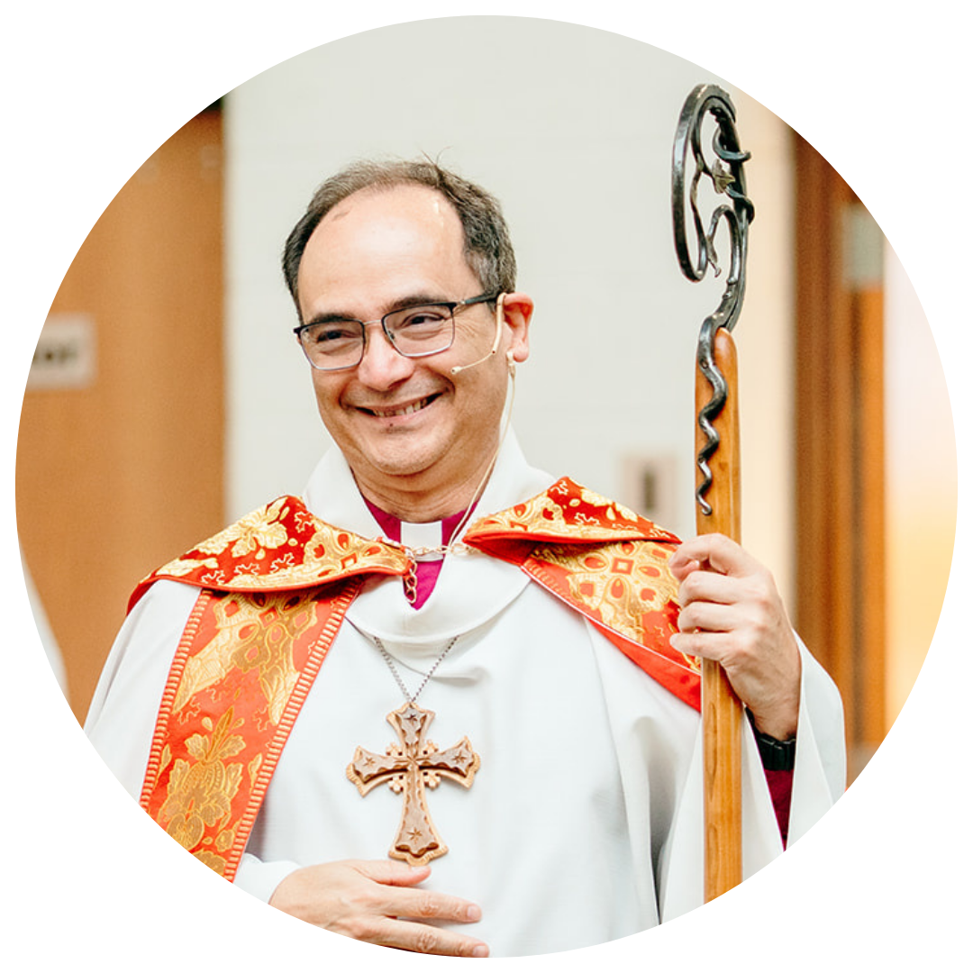 Bishop deForest in religious vestments, including a miter and a staff, smiles while looking at the camera.